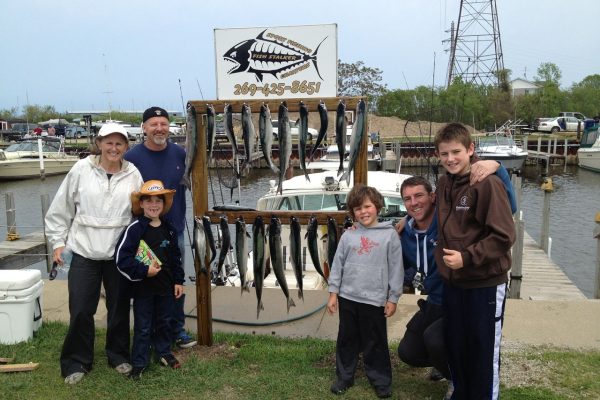 Group of people proudly displaying their catch of fish outdoors.