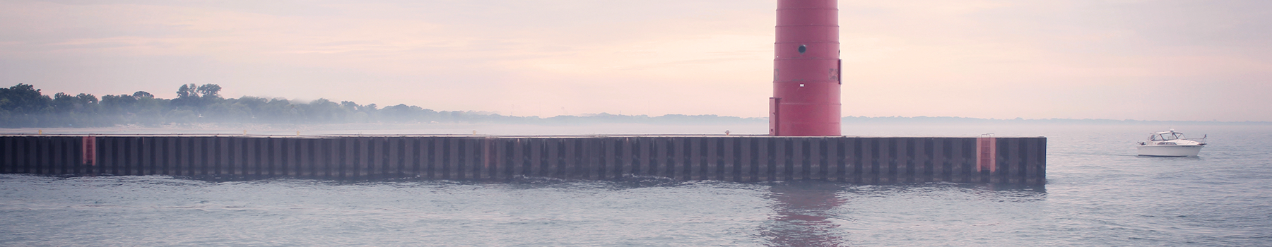 Calm sea with a long pier under a pastel sunset sky.